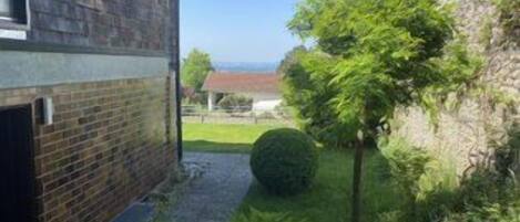 A residential property with a brick exterior, a paved driveway, and a well-maintained garden with a hedge and a spherical topiary.