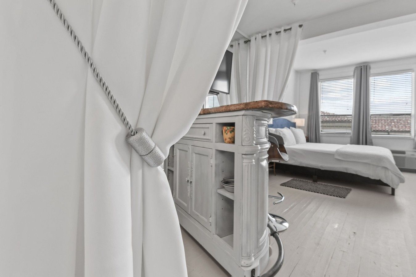 Une chambre d’hôtel moderne avec un lit, une petite armoire et une vue dégagée grâce à de grandes fenêtres.