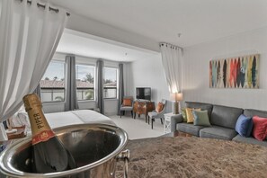 Una habitación de hotel con cama, televisión, sofá y un cuadro en la pared.