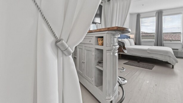 A modern hotel room with a bed, a small table, and a cabinet.
