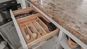 A kitchen drawer with utensils and a microwave.