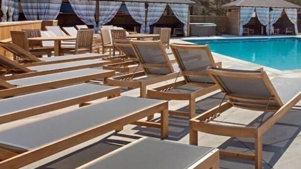 A poolside area with wooden lounge chairs and a covered seating area. - BRAND NEW! Whalehead Beach Mediterranean Inspired Villa (Corolla)