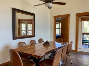 A dining area with a wooden table and chairs, a ceiling fan, and a large mirror on the wall.