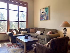 A cozy living room with a sectional sofa, a wooden coffee table, and a lamp.