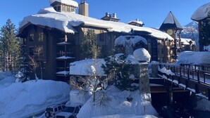 A snow-covered lodge with multiple balconies and a clock tower. - Spacious, top floor, tree views, tastefully remodeled condo, in The Village (Mammoth Lakes)