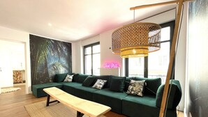 Ett modernt vardagsrum med en grön soffa, en träbänk och en lampa med flätad skärm.