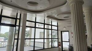 Un hall d’hôtel doté de grandes fenêtres, de colonnes blanches et d’un plafond aux lignes courbes.