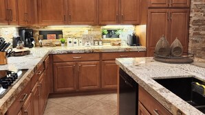 A kitchen with wooden cabinets, a granite countertop, a dishwasher, and a coffee maker.