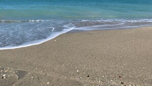 Ein Strand mit klarem, blauem Wasser und einem sandigen Ufer.