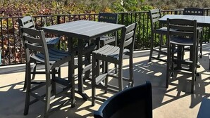 Eine Terrasse im Freien mit Tischen und Stühlen, mit Blick auf Strand und Meer.