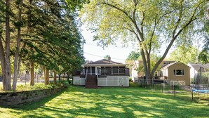 Una casa con patio trasero cercado, porche y una pequeña terraza.