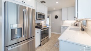 Una cocina moderna con electrodomésticos de acero inoxidable, armarios blancos y un salpicadero de baldosas en espiga.