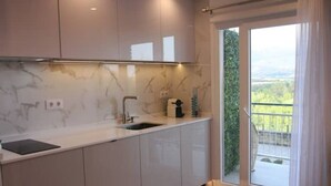 Una cocina moderna con salpicadero de mármol, un lavamanos y una ventana con vistas a un balcón.