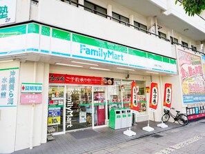 Un magasin FamilyMart avec une entrée bien visible, des distributeurs automatiques de billets et des poubelles de recyclage à l’extérieur.