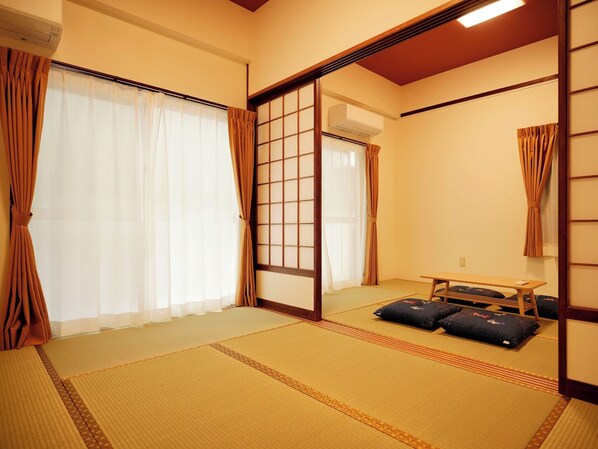 A traditional Japanese room with tatami flooring, sliding doors, and a low wooden table with cushions.