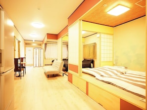 A hotel room with a bed, a chair, a desk, and a wardrobe.