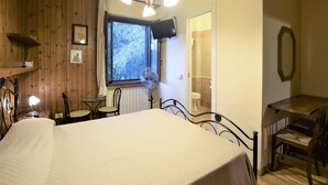 A room with a bed, a small table, two chairs, a window, a fan, a TV, and a mirror. - Lovely home in Rivotorto di Assisi (Rivotorto di Assisi)