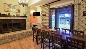 A dining area with a stone fireplace, wooden chairs, a wooden table, and a view of an outdoor patio. - Lovely home in Rivotorto di Assisi (Rivotorto di Assisi)