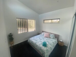 Relax in this serene bedroom with a large bed, potted plant, and reading lamp.