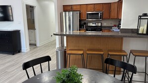 A modern kitchen with stainless steel appliances, wooden cabinets, and a bar area with stools. - Modern 3BR & 2BA Near McCormick & Downtown (Chicago)