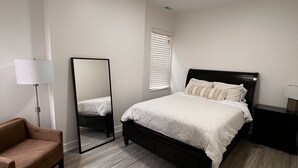 A bedroom with a bed, a mirror, a nightstand, a lamp, and a chair. - Modern 3BR & 2BA Near McCormick & Downtown (Chicago)