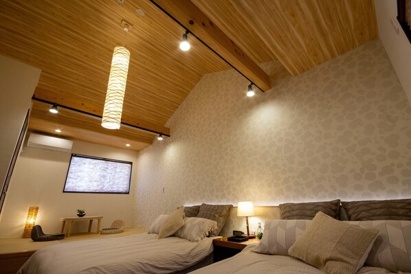 A modern bedroom with a wooden ceiling, a bed with multiple pillows, a bedside table with a lamp, and a small seating area with a chair and table. - A 5minute walk from JR Tofukuji Station a modern / Minami-ku， Kyoto Kyōto (Minami-ku， Kyoto)