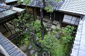 A traditional Japanese garden with stone lanterns, a small pond, and a wooden fence.