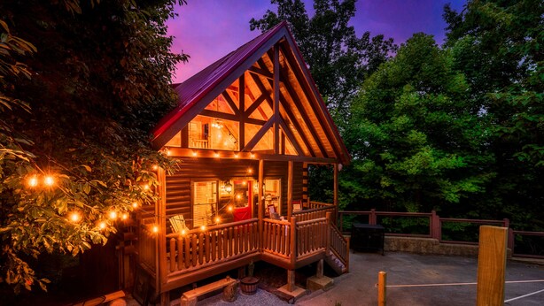 A wooden cabin with a porch, string lights, and a fire pit. - Stunning Fall Colors From Double Decks, 15 min to Gatlinburg, Firepit, HotTub (Sevierville)