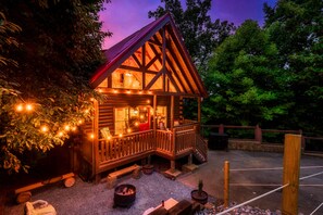 A wooden cabin with a porch, string lights, and a fire pit. - Stunning Fall Colors From Double Decks, 15 min to Gatlinburg, Firepit, HotTub (Sevierville)