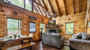 A wooden cabin interior with a dining table set, a sofa, and a fireplace. - Stunning Fall Colors From Double Decks, 15 min to Gatlinburg, Firepit, HotTub (Sevierville)