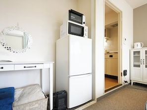 A compact kitchenette with a refrigerator, microwave, and a small sink.