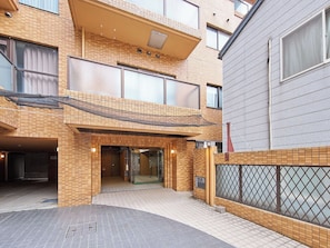 A multi-story building with a tiled facade, a covered entrance, and a gated area.