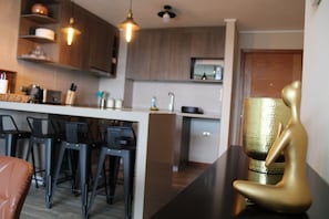 A modern kitchen with a central island, bar stools, and pendant lighting.