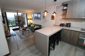 A modern kitchen with a large island, bar stools, and a coffee station.