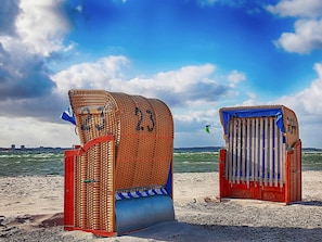 Deux cabanes de plage, numérotées 23 et 24, situées sur une plage de sable, avec la mer en arrière-plan.