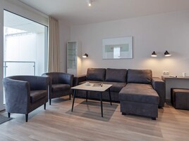 Ein modernes Wohnzimmer mit einer Couch, zwei Sesseln, einem Couchtisch und einer Glaskabine.