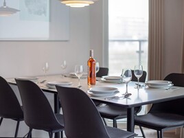 Comedor con una mesa dispuesta para cuatro, sillas y una botella de vino.