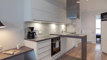 Una cocina moderna con horno empotrado, cafetera y microondas.