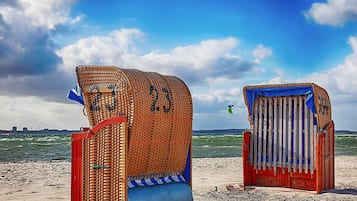 Dos cabañas de playa con los números 23 y 24, situadas en una playa arenosa con el mar al fondo.