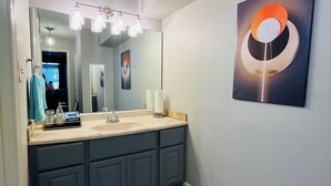 Un baño con un espejo grande, un lavabo y un perchero para toallas.
