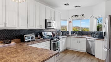 A modern kitchen with white cabinets, a microwave, a toaster, and a dishwasher.
