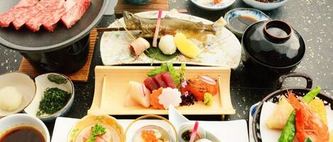 A variety of Japanese dishes including sushi, sashimi, and tempura, arranged on a table with a black tablecloth.