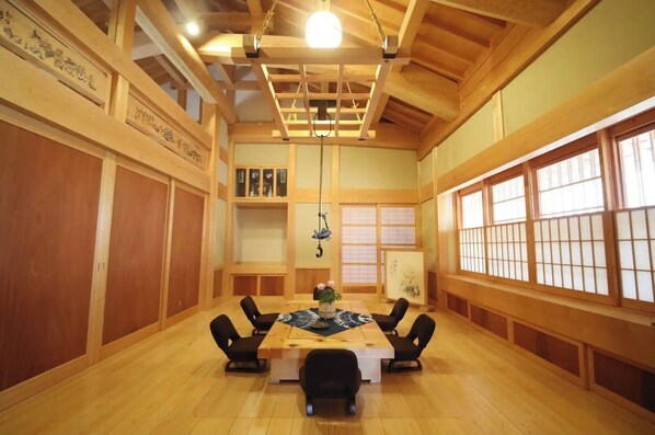 Une pièce de style japonais traditionnel, avec une table recouverte d’un tatami, des portes coulissantes en bois et une décoration suspendue.