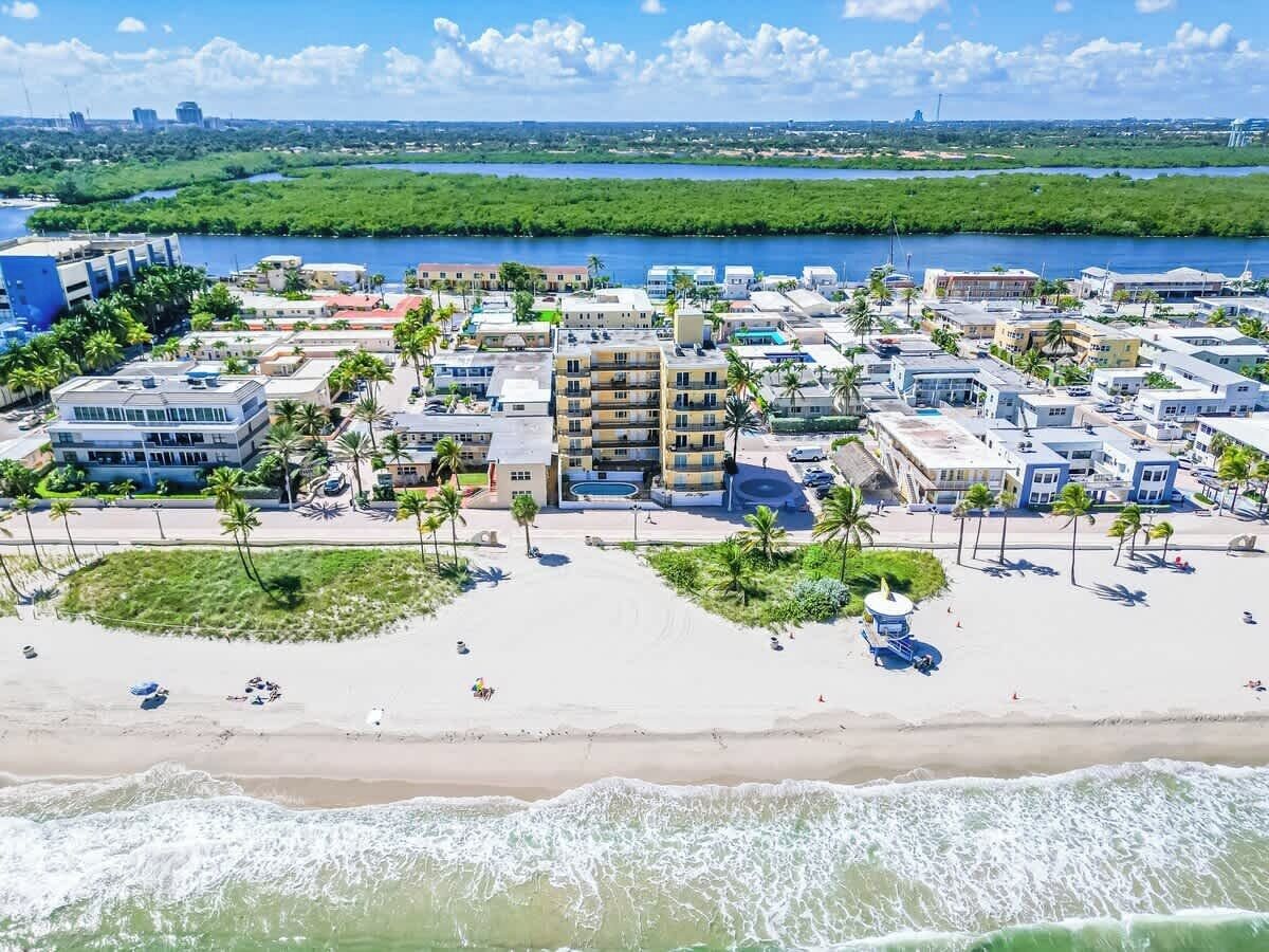 A coastal resort with beachfront villas, palm trees, and a view of the ocean.