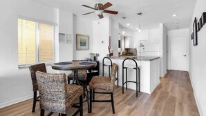 A modern kitchen with a central island, a dining area with wicker chairs, and a ceiling fan. - Beachfront 1BR · Ocean View, Pool + Free Parking (Hollywood)