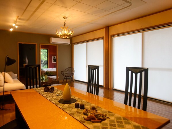 Ein traditioneller japanischer Raum mit Tatami-Böden, einem niedrigen Tisch mit dekorativer Mittelstück, verschiebbaren Shoji-Türen und einer Deckenleuchte.