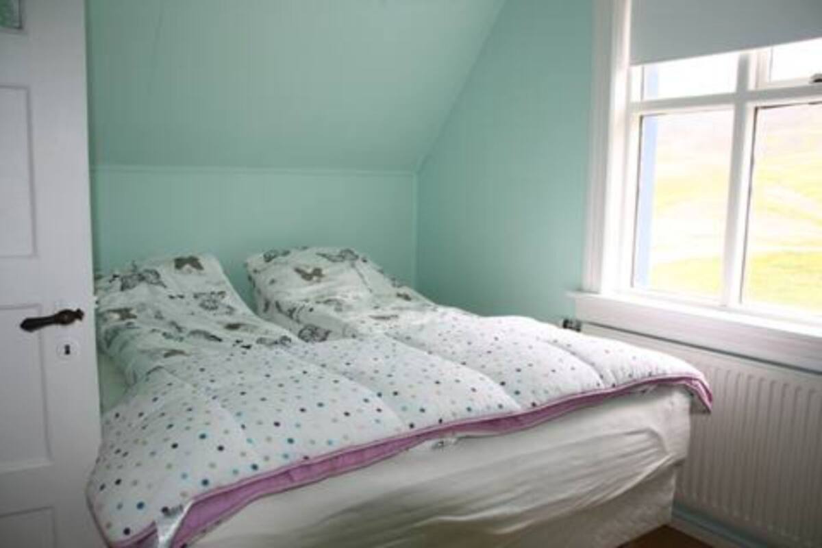 Een slaapkamer met een bed, een raam en een deur.