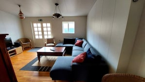 Een woonkamer met een bank, een salontafel, een televisie en een raam.