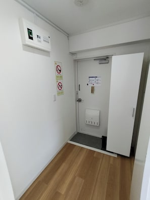 Ein Flur mit einer Tür, einer Wand-Klimaanlage und einem Rauchverbot-Schild.