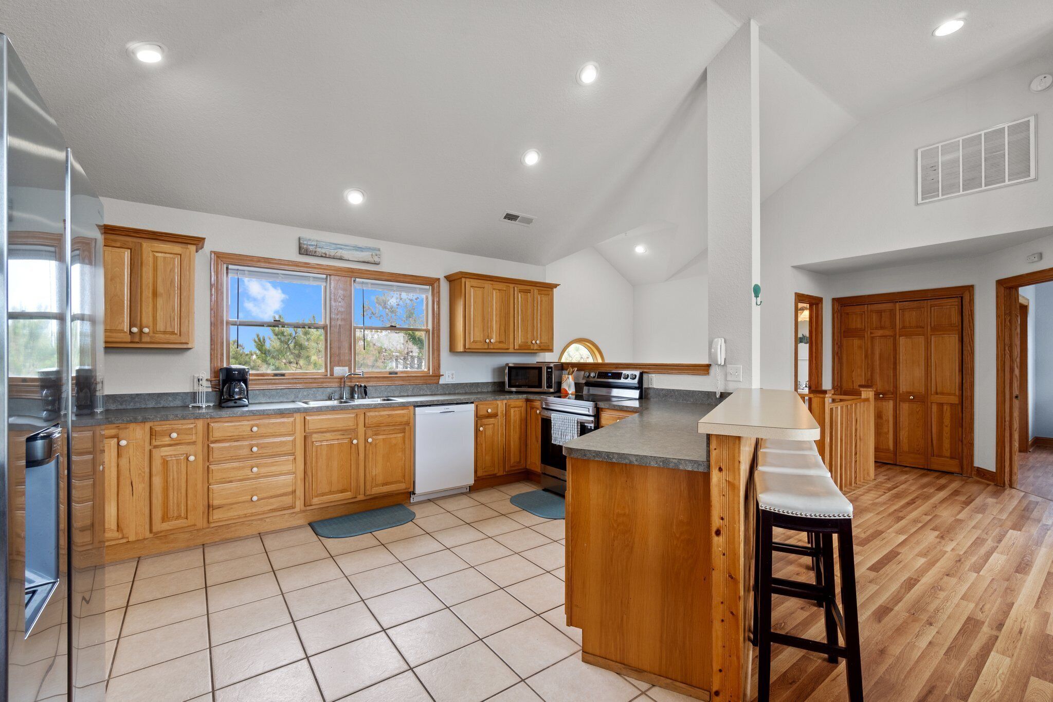 A spacious kitchen with wooden cabinets, a central island, and a large window.